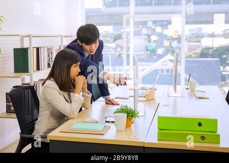 Two male and female staff Asians helped to plan a table full of documents and tablets, notebooks. Stock Photo