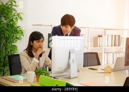 Two male and female staff Asians helped to plan a table full of documents and tablets, notebooks. Stock Photo