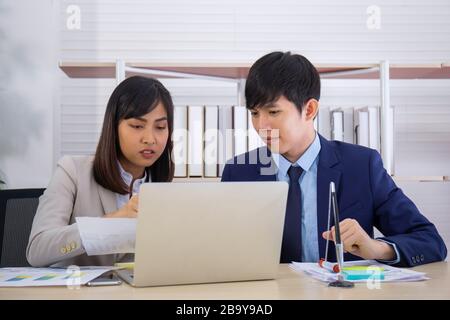 Two male and female staff Asians helped to plan a table full of documents and tablets, notebooks. Stock Photo