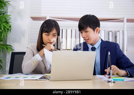 Two male and female staff Asians helped to plan a table full of documents and tablets, notebooks. Stock Photo