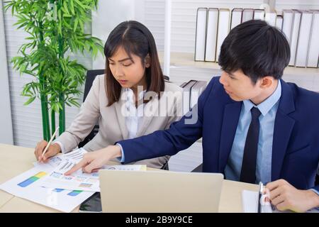 Two male and female staff Asians helped to plan a table full of documents and tablets, notebooks. Stock Photo