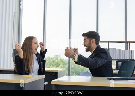 Two young businessmen, men and women, who showed great joy at the office with smiles and happiness. Stock Photo