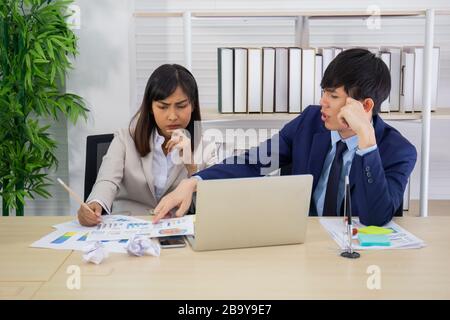 Two male and female staff Asians helped to plan a table full of documents and tablets, notebooks. Stock Photo