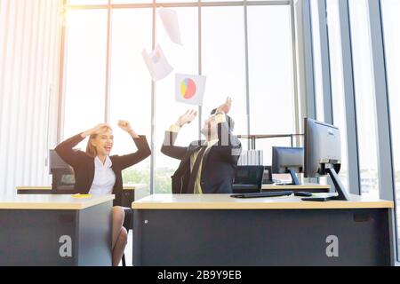 Two young businessmen, men and women, work at the office with a tablet and accompanying documents on the desk with smiles and happiness. Stock Photo