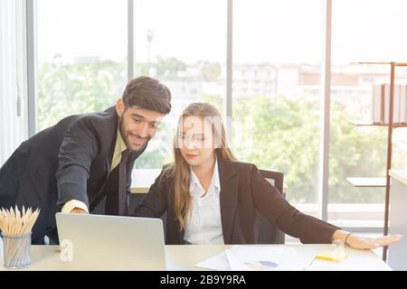 Young businesspeople working at the office with laptops and documents on their desks. With a good smile And has a beautiful orange fair Stock Photo