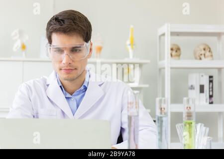 The concept of health care researchers working in biological science laboratories The young male research scientist is preparing and analyzing a slide Stock Photo