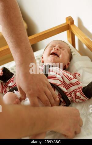 Parent changing baby's diaper indoors, Stock Photo
