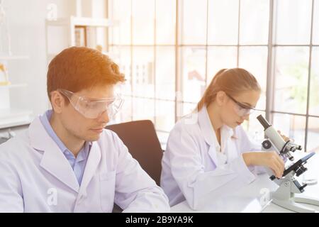 concept of a healthcare researcher, a researcher working in a life science lab, a young research scientist and a male supervisor preparing and analyzi Stock Photo