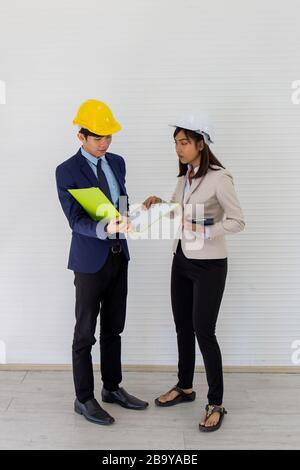 Two Asian male and female foreman wearing a helmet and standing and talking at the event site Stock Photo