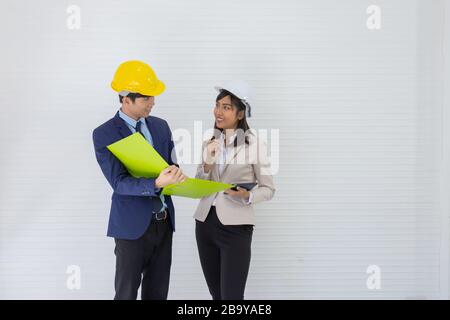 Two Asian male and female foreman wearing a helmet and standing and talking at the event site Stock Photo