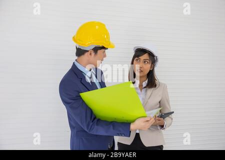 Two Asian male and female foreman wearing a helmet and standing and talking at the event site Stock Photo