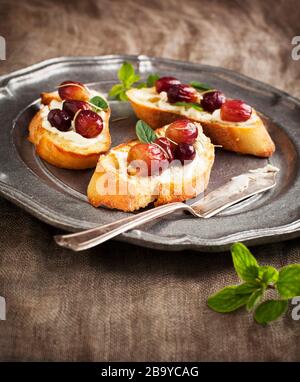 Crostini with goat cheese, grapes and rosemary Stock Photo - Alamy