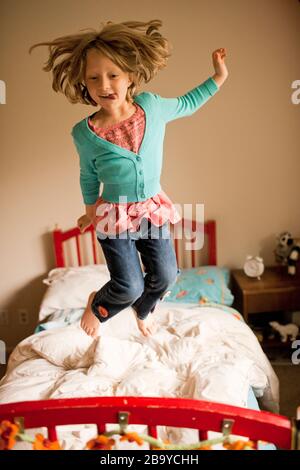 Girl jumping up and down on  her bed. Stock Photo