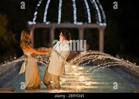 Happy mid adult couple dancing in a fountain. Stock Photo