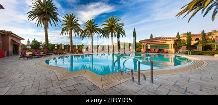 Deck chairs lined up near a luxury swimming pool. Stock Photo