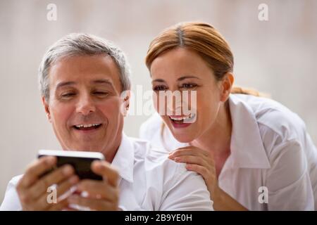 Professional couple looking at something on an iphone. Stock Photo