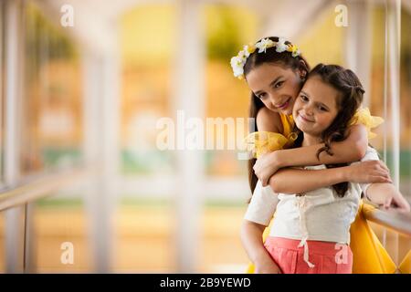 Smiling girl standing with arms around sister. Stock Photo