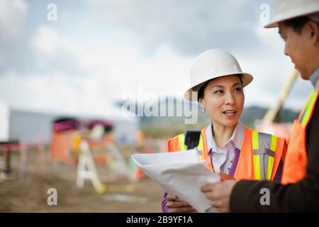 Two colleagues discussing a project on a construction site. Stock Photo