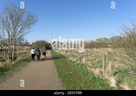 25 March 2020. King's Lynn, Norfolk, UK.  Family groups give children their daily exercise during the Covid-19 Coronavirus pandemic while trying to maintain the required social distancing from other people.  Credit: UrbanImages-News/Alamy Stock Photo