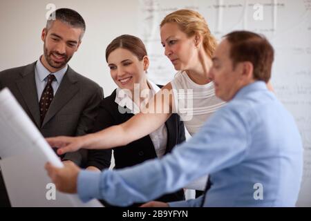 Small group of business people in a meeting looking at building plans. Stock Photo