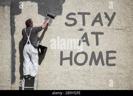 Man painting wall. Stay at home added in Photoshop. Stock Photo