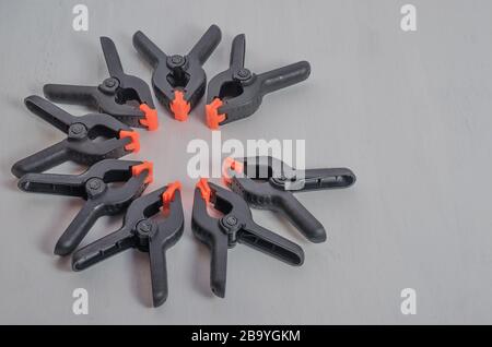 Black and orange construction clamps on a white background. Set of medium plastic clips. Clamping tools for carpentry. Hand tools for needlework. Clam Stock Photo