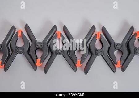Black and orange construction clamps on a white background. Set of medium plastic clips. Clamping tools for carpentry. Hand tools for needlework. Clam Stock Photo