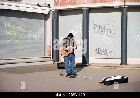 A busker plays on the deserted streets at Brighton beach after Prime Minister Boris Johnson made the decision to put the UK in lockdown to help curb the spread of the coronavirus. Stock Photo