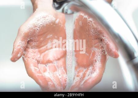 Hands under running sink faucet washing with soap and warm water. Stock Photo