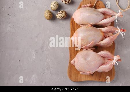 Fresh raw organic quails on wooden board and quail eggs on a gray background, Copy space Stock Photo