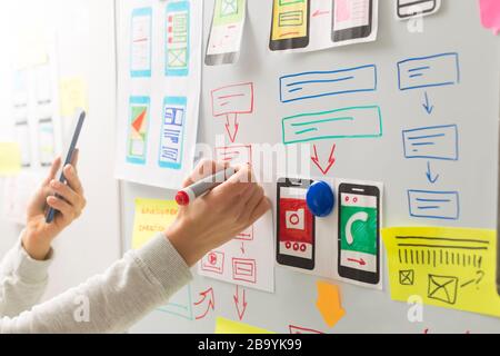 A web designer is developing a user interface for mobile phone applications. User experience. Stock Photo