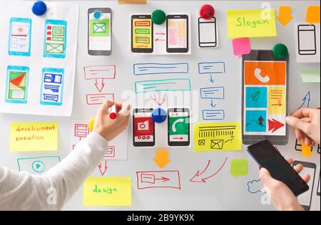 A web designer is developing a user interface for mobile phone applications. User experience. Stock Photo