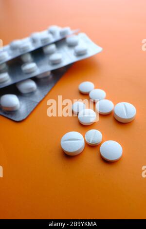 colorful pills spilling on orange background, top view Stock Photo