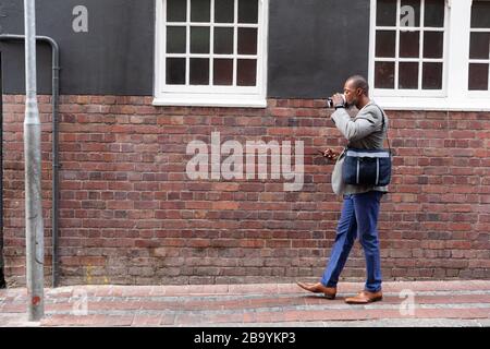 African American man walking and using his phone in the street Stock Photo