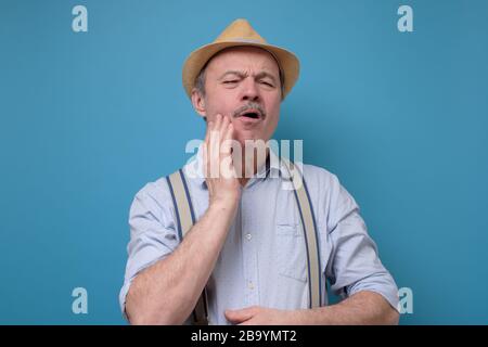 man in summer hat frowning having toothache touching his cheek Stock Photo
