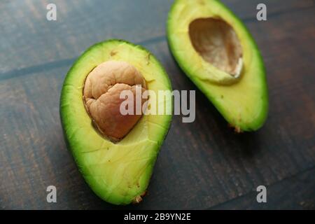 close up of slice of avocado on wooden table. Stock Photo