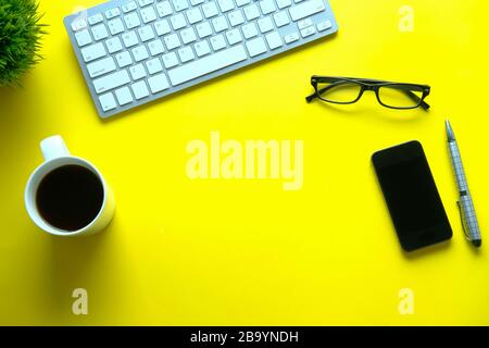 top view of keyboard ,smart phone and tea on yellow background  Stock Photo