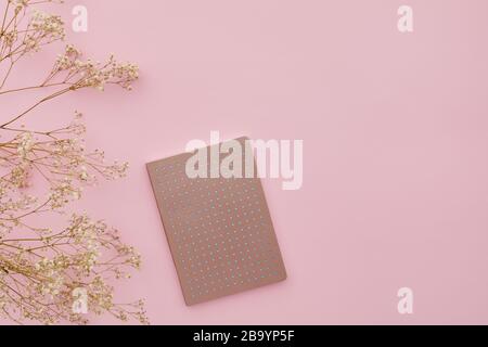 flat lay gypsophila flowers and a diary on pink background, top view. empty space for text. Stock Photo