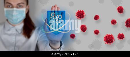 Young doctor in a medical mask shows stop viruses or cancer on a gray background. Attack of red infected cells. Immunity protective shield against bacteria Stock Photo