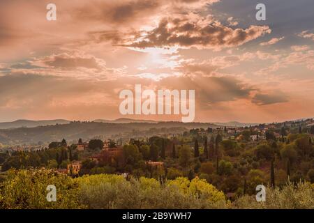 Classic Tuscany landscape with the mid-afternoon sun and its rays illuminating the green hills, cypresses, pines and villas Stock Photo