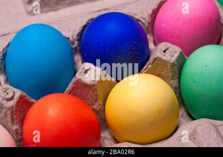 Close-up of blue, pink, red, yellow and green dyed easter eggs arranged in cardboard egg carton Stock Photo