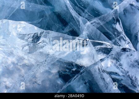 Beautiful cracked ice on the lake. Clear blue ice with white cracks. Horizontal. Stock Photo