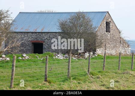 A large lone stone built building with a new roof situated on a hill top overlooking Bridgend in South Wales. Stock Photo