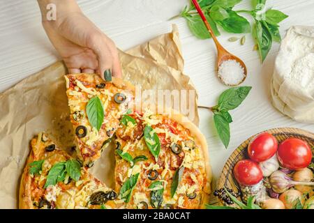 Hands taking slices of pizza. Hand holding slice pizza. Hand taking pizza slices from white wooden background Stock Photo