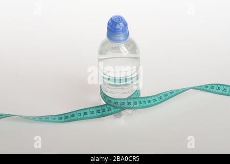 Water bottle tied with cyan measure tape on white background