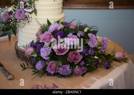 Brides bouquet sitting next to the wedding cake. pink roses and carnations in the brides wedding bouquet Stock Photo