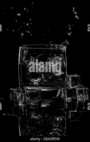 water splashing in a glass of water and ice on black background Stock Photo