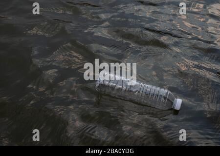 Used waste plastic bottle floating on water in a canal, Eco-friendly approach Environmental and Pollution Concept Stock Photo