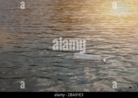 Used waste plastic bottle floating on water in a canal, Eco-friendly approach Environmental and Pollution Concept Stock Photo