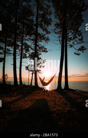Sitting in a hammock with a peace sign overlooking the sunset social distancing Stock Photo